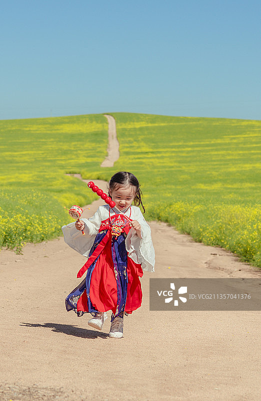 穿汉服的小女孩举着糖葫芦在油茶花山路上欢快奔跑图片素材