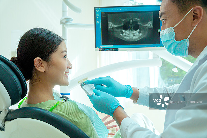 牙科医生在给女性患者对比牙齿色号图片素材