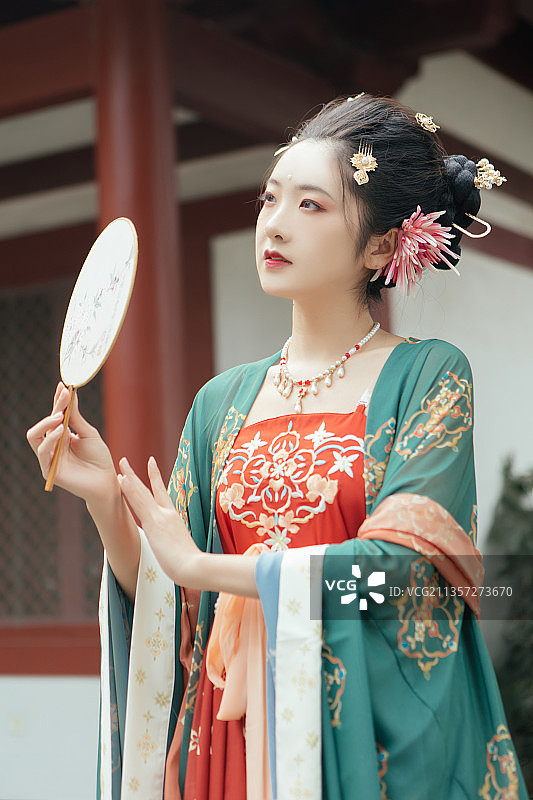 亚洲美女穿着汉服在户外历史建筑前拿着扇子休息图片素材