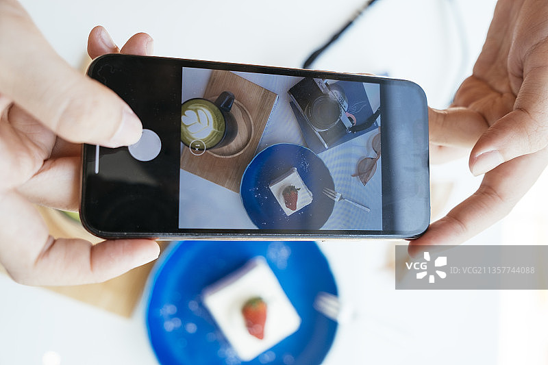 复制空间-女人的手在拍摄甜点。相机先吃。图片素材