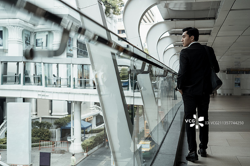 后视图-年轻的亚洲泰国商人穿着黑色正装走在曼谷的人行道上。图片素材