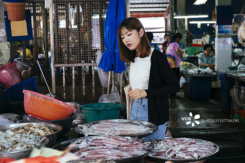 年轻的亚洲泰国妇女在泰国当地市场挑选海鲜。图片素材