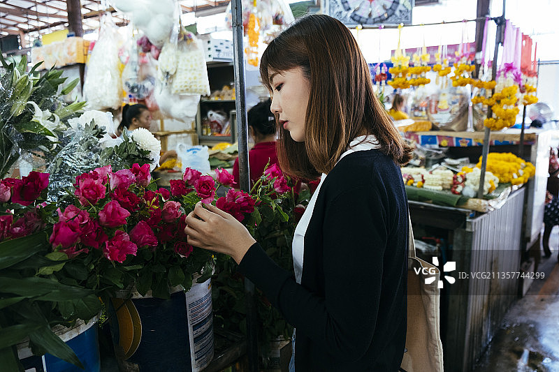 年轻的泰国亚洲妇女在泰国当地市场购买玫瑰花。图片素材