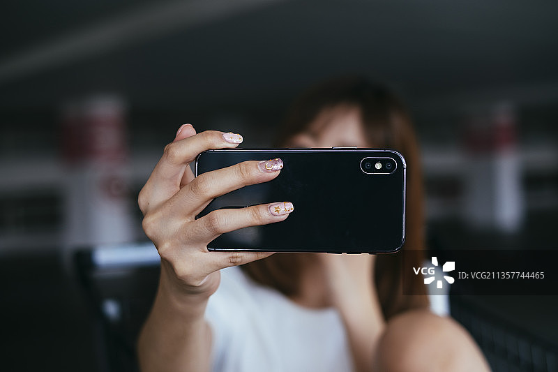 年轻的亚洲泰国女人用智能手机自拍。近手女人使用智能手机前置摄像头。图片素材