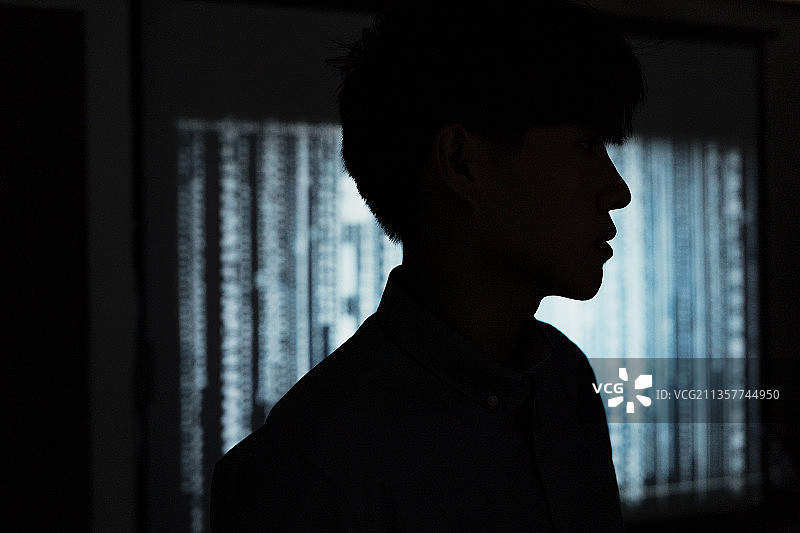 黑客在服务器室内工作的剪影。黑暗中的黑客。图片素材