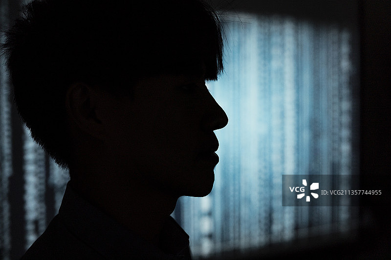 黑客在服务器室内工作的剪影。黑暗中的黑客。图片素材