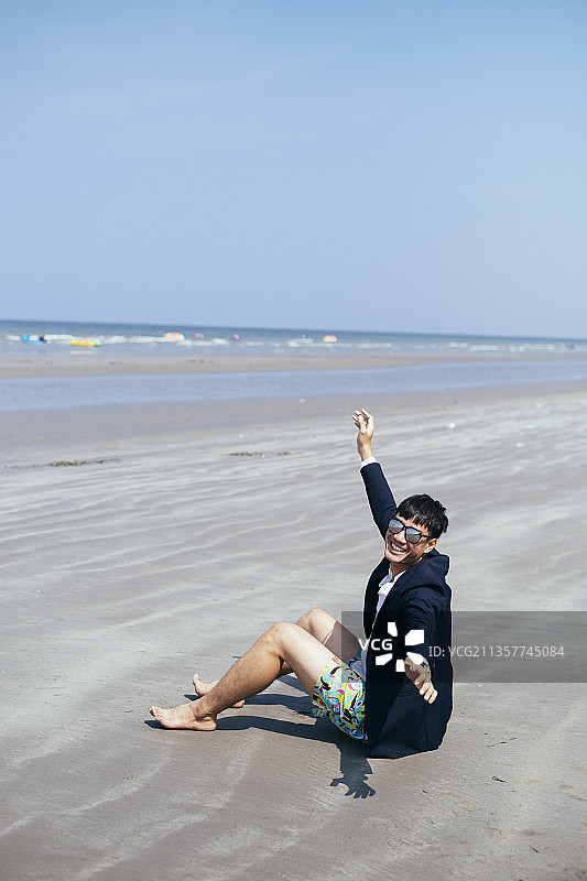 商人在沙滩上放松，坐在沙滩上。在周末加速时间。图片素材