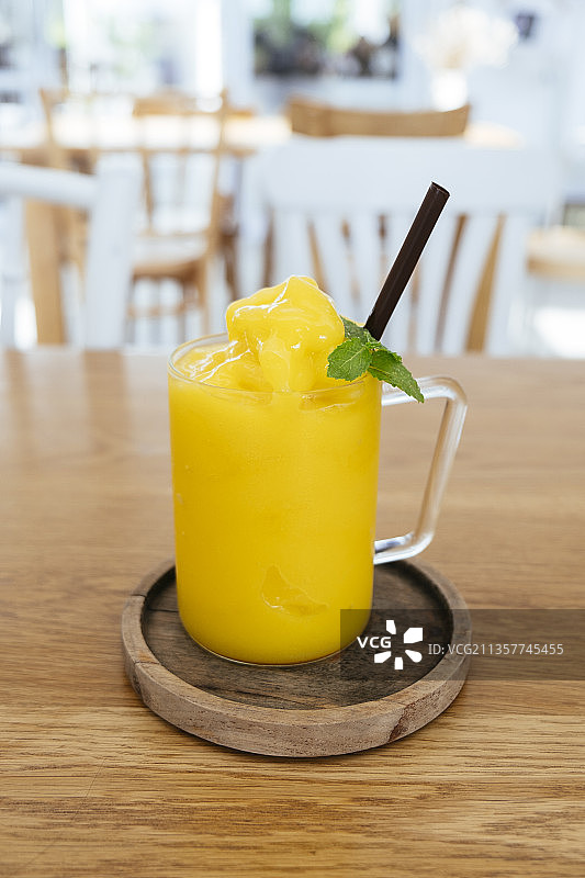 木桌上的玻璃杯装芒果冰沙。图片素材