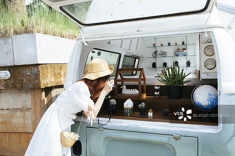 年轻的亚洲旅行者泰国妇女穿着白色的衣服和帽子使用无镜相机。图片素材