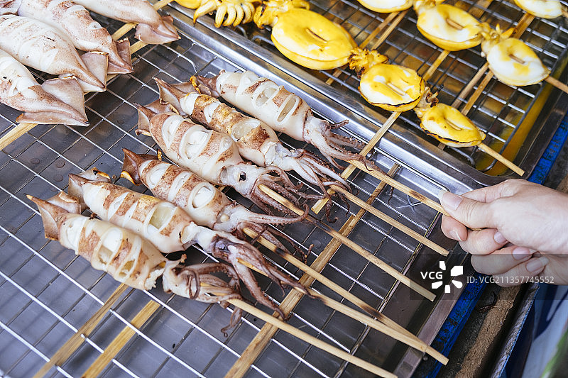 美味的木棒烤鱿鱼-街头小吃。图片素材