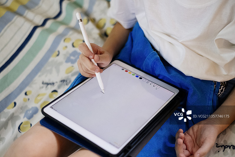 一个孩子的手用笔在数码平板上画画。模拟。副本的空间。图片素材