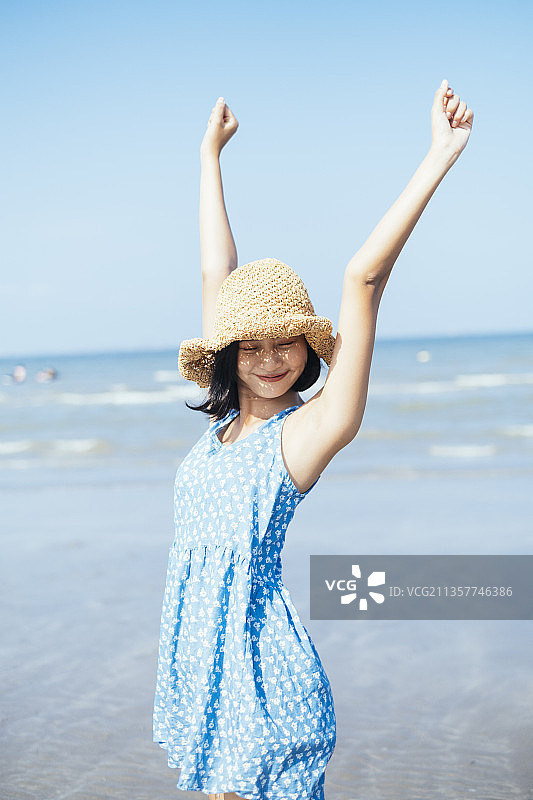 活泼可爱的蓝色连衣裙女孩在夏天清新的海边。图片素材