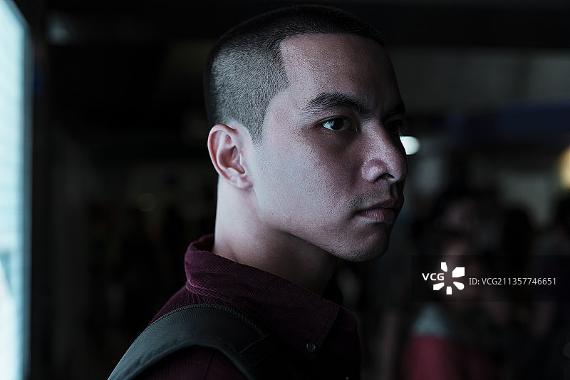 光头党穿着红衬衫站在有LED显示屏的黑暗房间里。图片素材