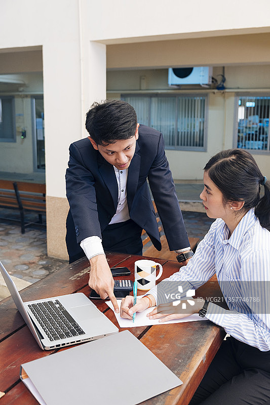 一个男人让一个女人修改文件上面的信息。图片素材