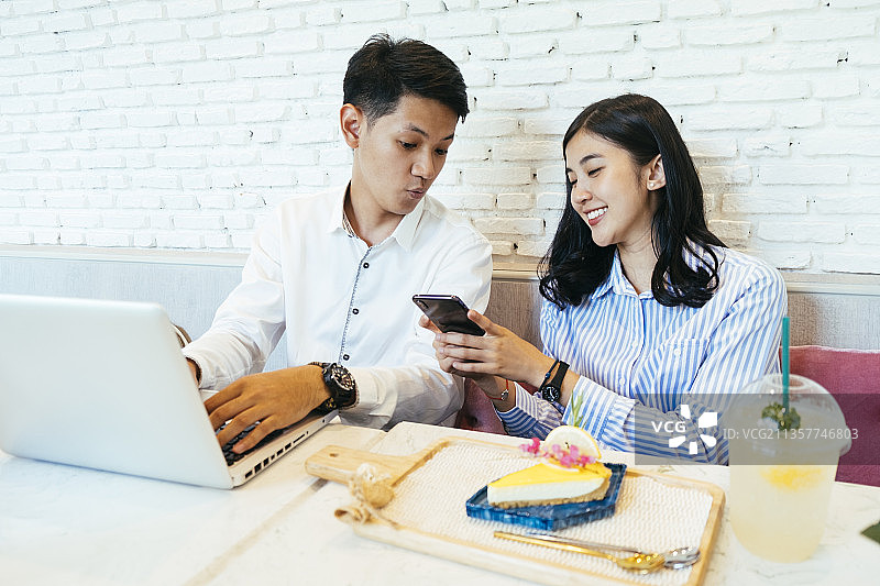 男人和女人在咖啡馆用蛋糕和饮料做他们的工作。图片素材
