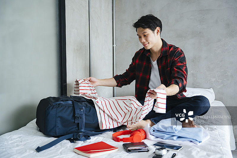 亚洲年轻人为旅行打包衣服和东西。图片素材