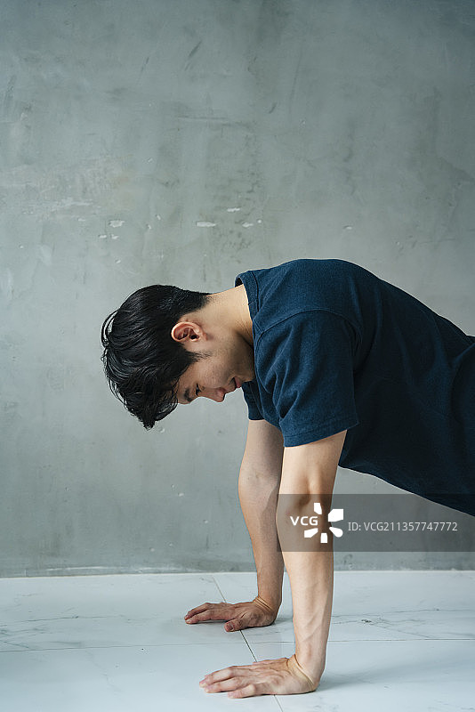 侧视-亚洲年轻人在健身房做俯卧撑。图片素材