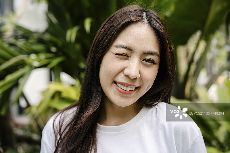 花园中欢快微笑的美丽亚洲女人的肖像。图片素材