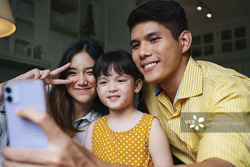 亚洲家庭用智能手机自拍。图片素材