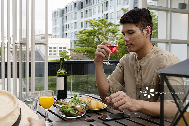 一个亚洲男人和他的女朋友在咖啡厅里喝红酒。图片素材