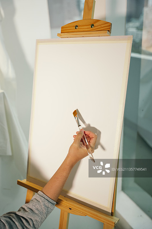 艺术家用毛笔在木架上的空画布上作画。图片素材