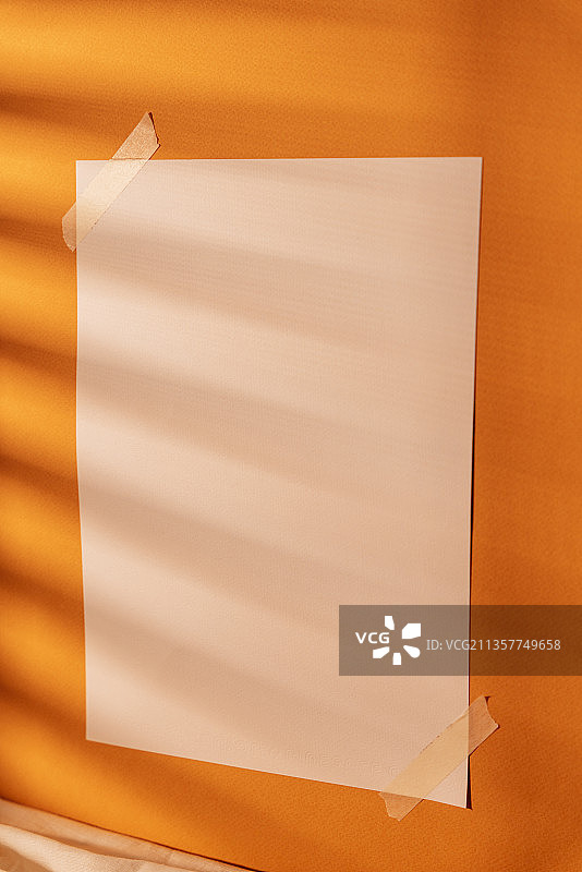 在自然光的房间里，橙色墙壁上的空白纸。模拟和复制空间设计。图片素材