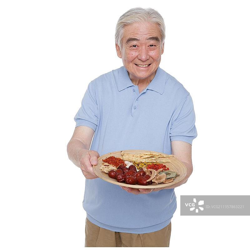 一个老年男人拿着中草药图片素材