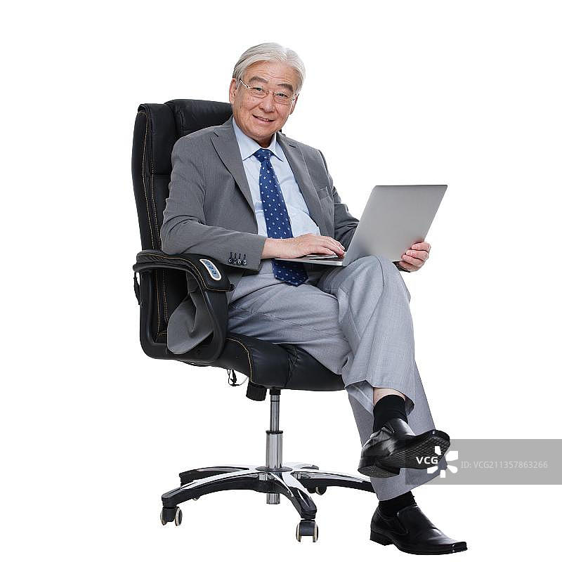 一个老年男人坐在老板椅上使用电脑图片素材