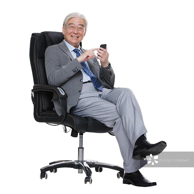 一个商务老年男人拿着手机坐在老板椅上图片素材
