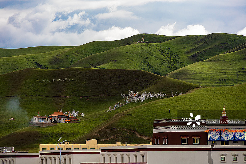 多云天气，甘肃甘南合作市，高山草甸和山间的藏传佛教寺庙建筑。图片素材