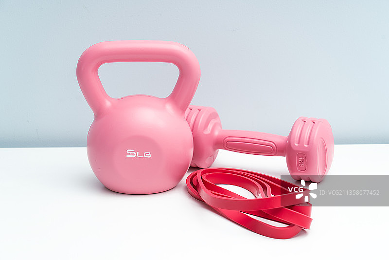 粉红色的哑铃和提壶哑铃放在白色桌面上图片素材