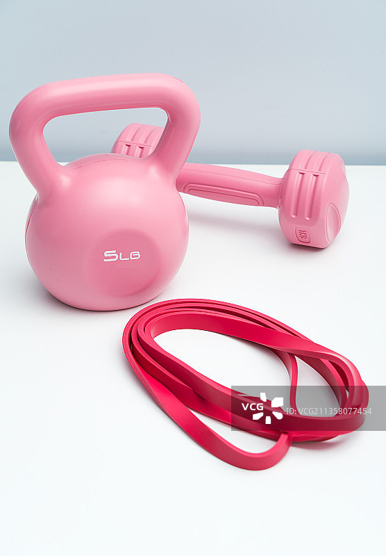 粉红色的哑铃和提壶哑铃放在白色桌面上图片素材