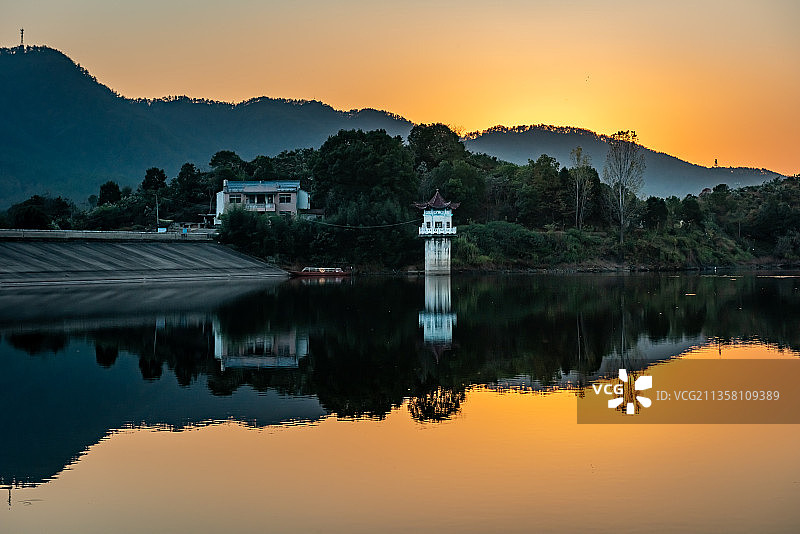 日落时有亭子和山倒影的湖图片素材