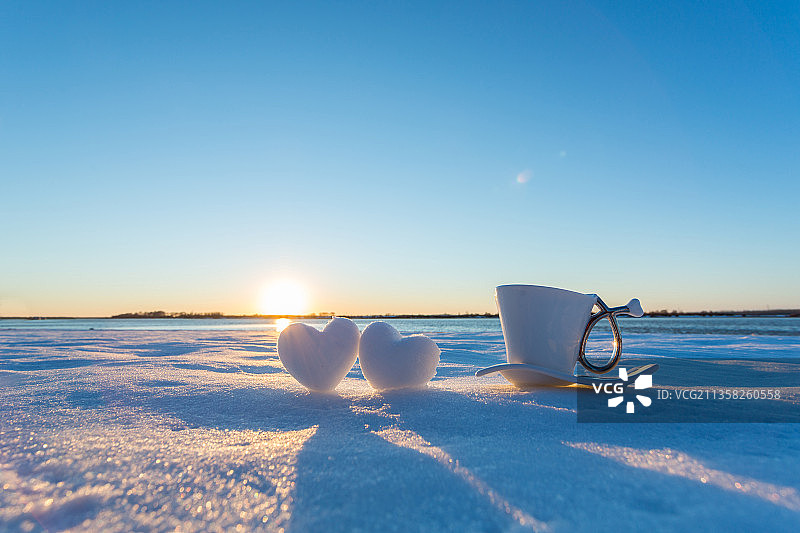 夕阳下的咖啡杯与心形雪球，一辈子的爱图片素材
