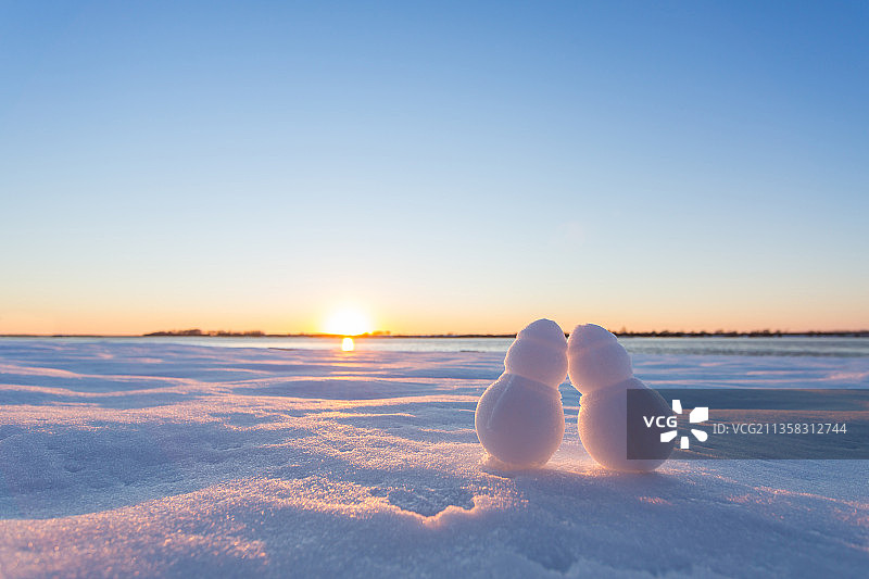 冬天日落时分雪地上的两个小雪人图片素材