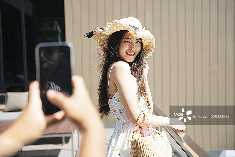 美丽的亚洲女游客正在用智能手机和她的朋友拍照。图片素材