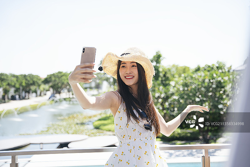 美丽的亚洲女人旅游视频与智能手机在酒店。图片素材