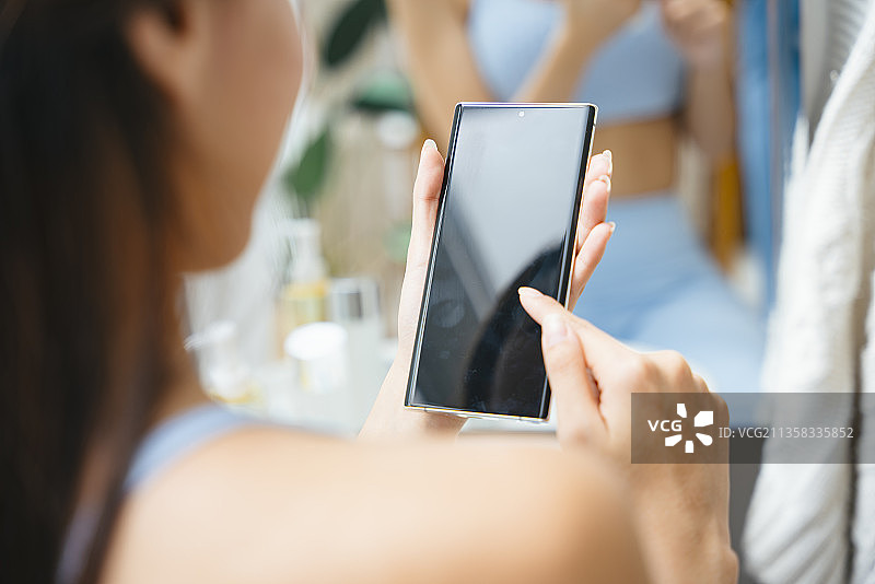 健康女性在家用智能手机购物。图片素材