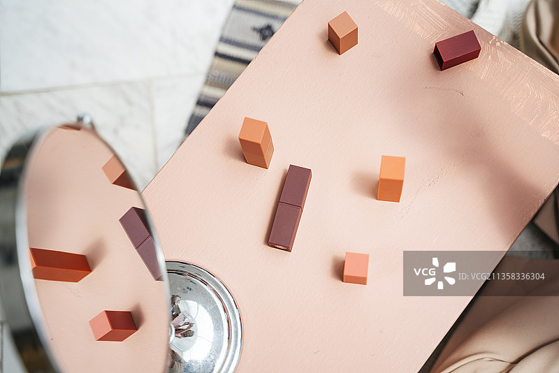 粉红色的桌子上有许多化妆品和镜子。图片素材