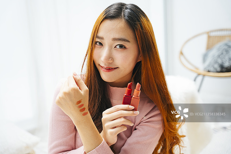 美丽的亚洲女性影响评论口红的社交媒体观众。图片素材