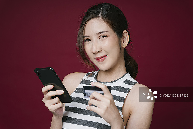 近肖像美丽的年轻亚洲妇女使用智能手机和信用卡网上购物图片素材