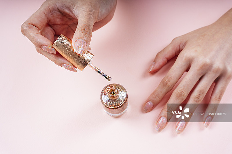 女性手涂亮金色指甲。图片素材