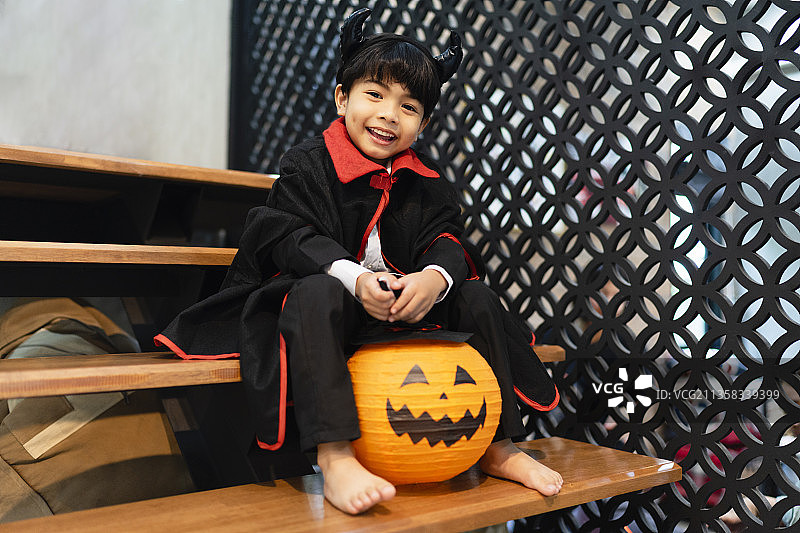 晚会上穿着万圣节服装的小男孩和南瓜气球。图片素材
