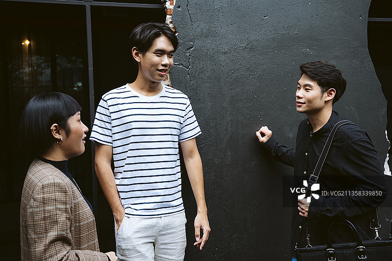 三个穿着休闲衬衫的年轻商人在咖啡馆会面后休息。图片素材