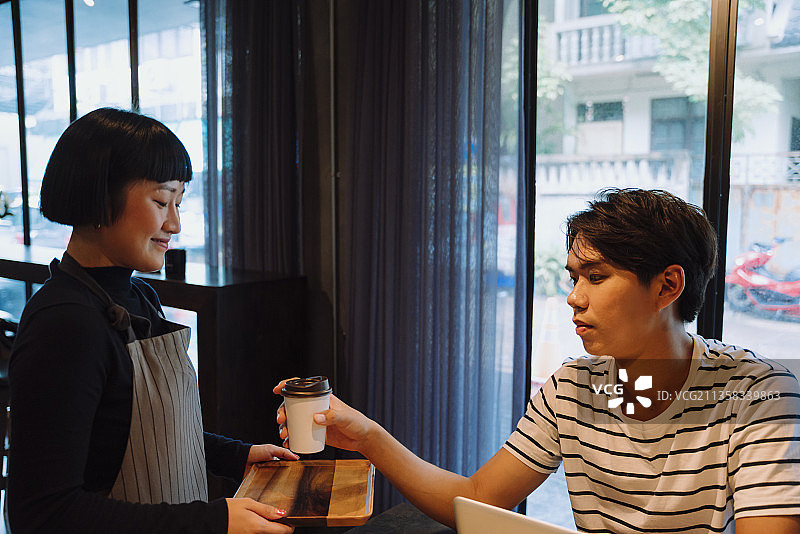 在自助餐厅为顾客提供热咖啡的亚洲女服务员。图片素材