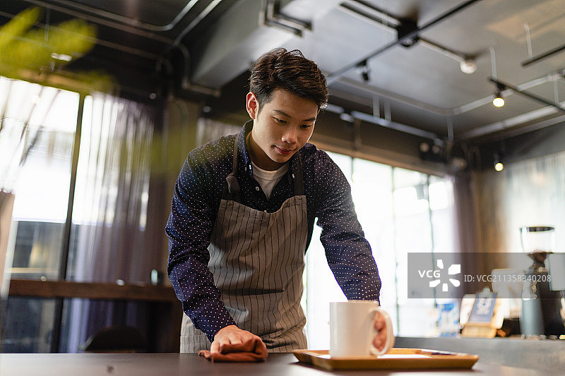 亚洲服务员清洁咖啡吧预防covid-19。图片素材