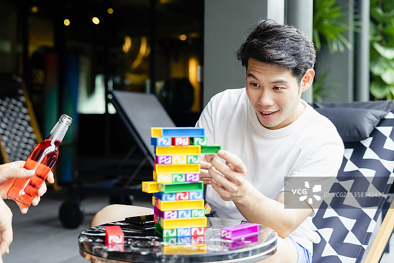身穿白衬衫的亚洲男子在派对上玩积木。图片素材