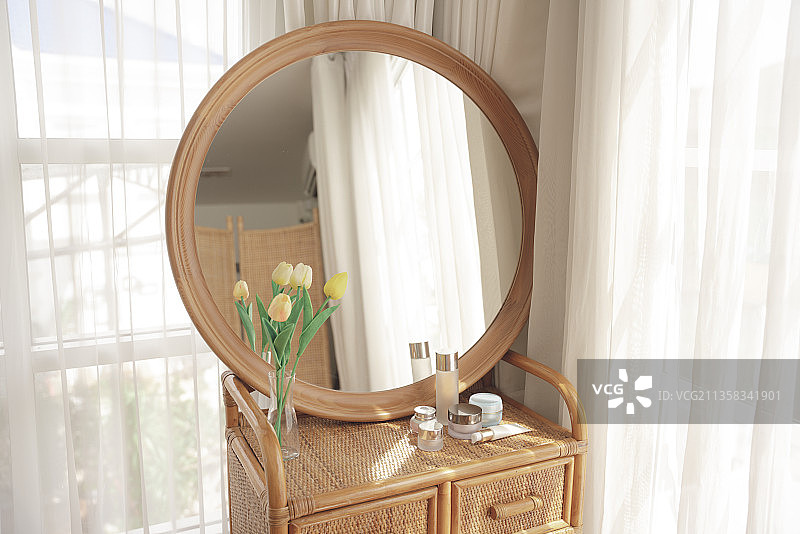 白色房间里的化妆桌、圆镜、花和化妆用具。图片素材