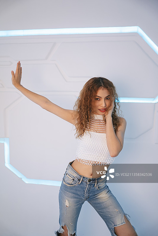 时尚肖像年轻的亚洲卷发在性感的衬衫和牛仔裤在现代的房间。图片素材