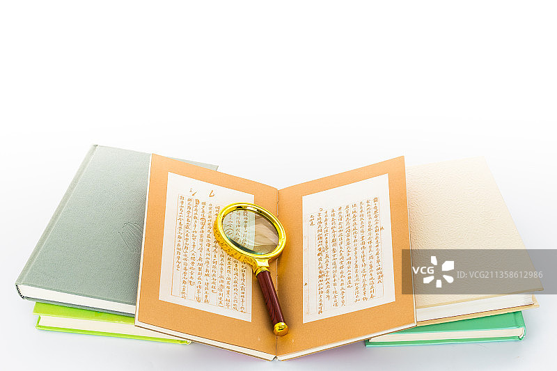 白色背景里放着一堆书和一个放大镜图片素材